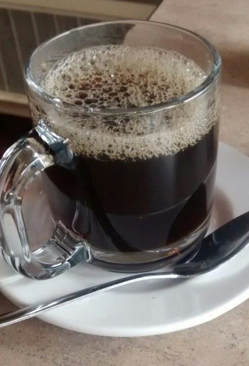 Mug of black coffee on a saucer with a spoon